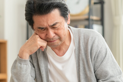 頬に手を当てて物忘れや考えごとに悩む男性のイメージ