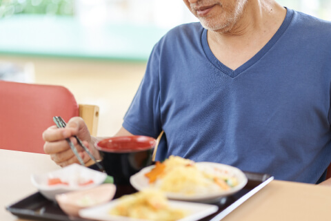 箸を持って食事をとる高齢男性のイメージ